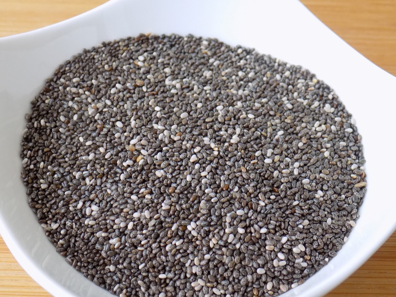 Semi di chia in un cucchiaio su sfondo bianco, simbolo di benefici per colesterolo e glicemia.