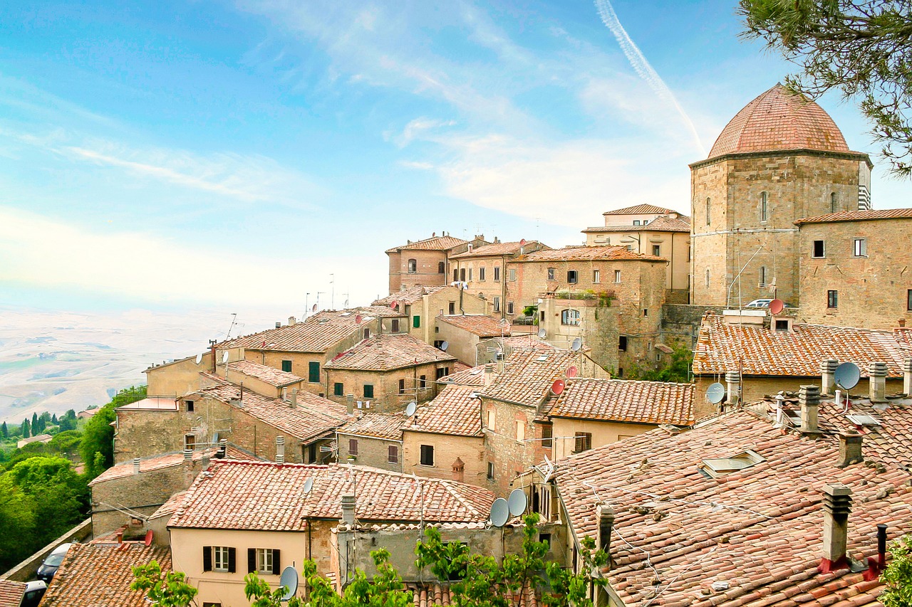 Panorama del borgo toscano con case in pietra e colline verdi sullo sfondo.