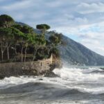 Spiaggia affollata in una località marina economica della Liguria, con ombrelloni e bagnanti.