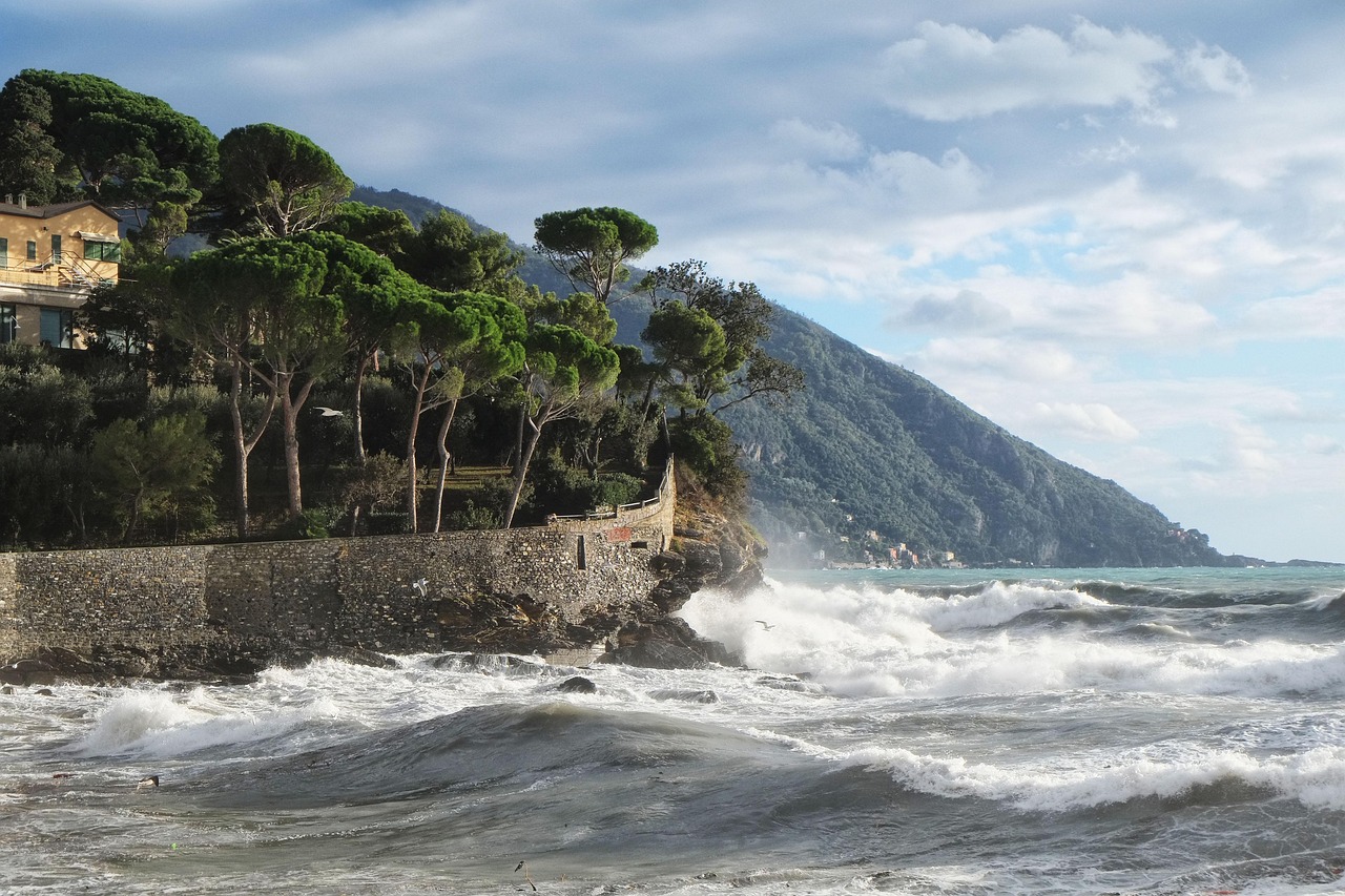 Spiaggia affollata in una località marina economica della Liguria, con ombrelloni e bagnanti.