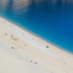 Spiaggia affollata con ombrelloni colorati, rappresentativa delle mete di mare economiche in Europa.