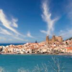 Panorama di Sciacca con terme e piatti di pesce fresco in primo piano.