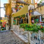 Stradine affascinanti di un borgo ligure, con il mare sullo sfondo e piante di basilico in primo piano.