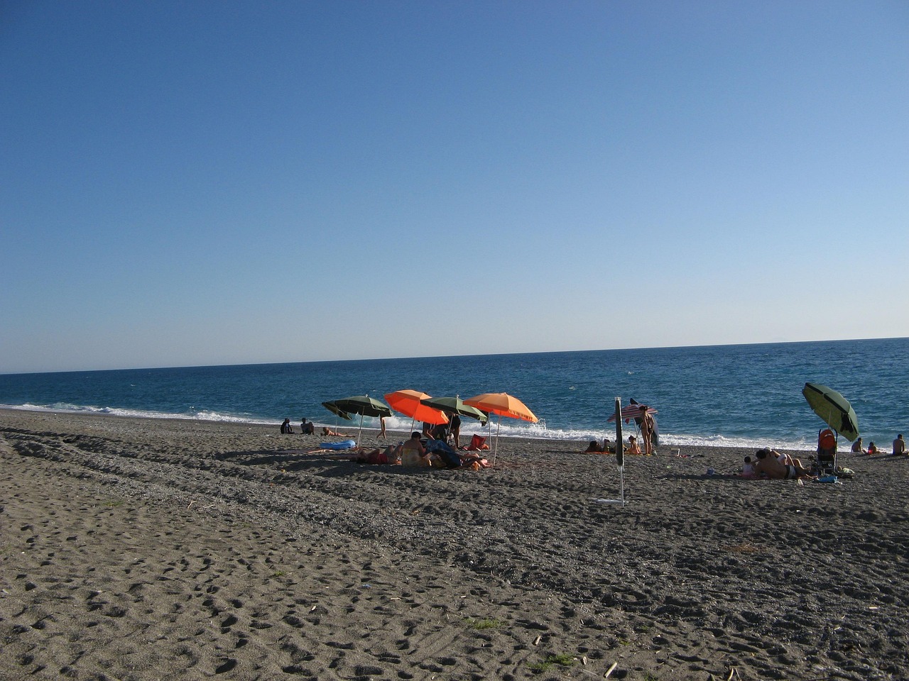 Spiaggia di Monterosso al Mare con sabbia dorata e acqua cristallina sotto un cielo azzurro.