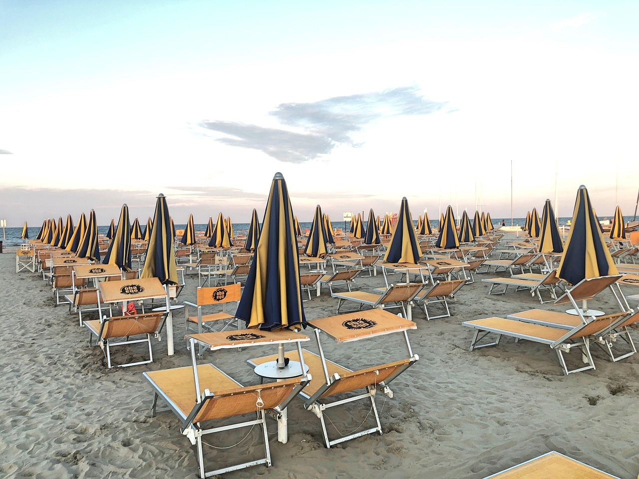 Spiaggia del Veneto con sabbia dorata e mare cristallino, affollata da turisti e bagnanti.