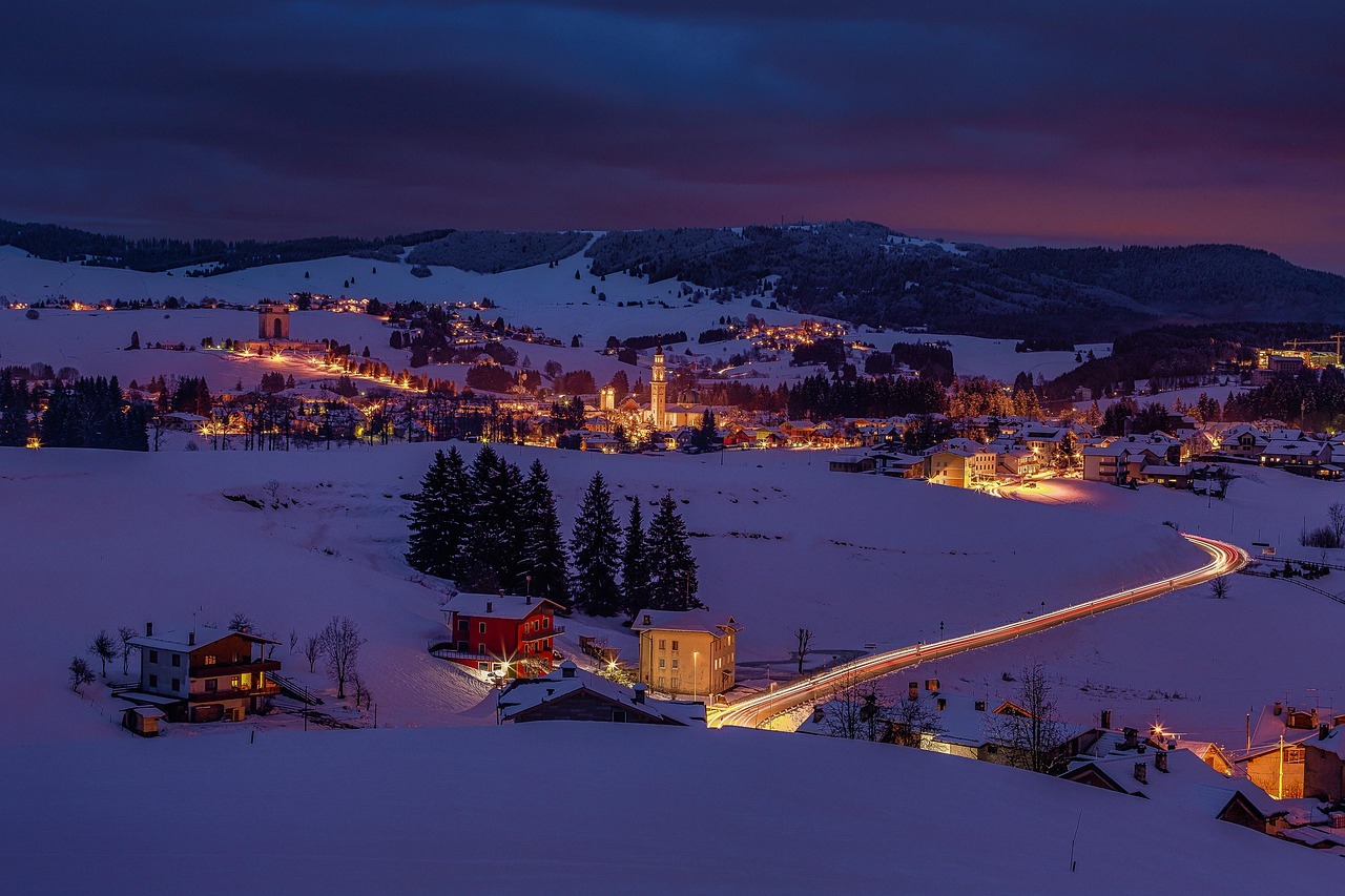 Panorama di una località alpina innevata, con chalet e figuranti in costume natalizio.