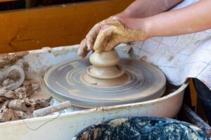 Vasaio al lavoro su tornio, creando ceramiche a Grottaglie, simbolo di tradizione artigianale.