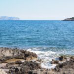 Spiaggia di Maiorca affollata con sabbia dorata e mare cristallino sotto un cielo azzurro.