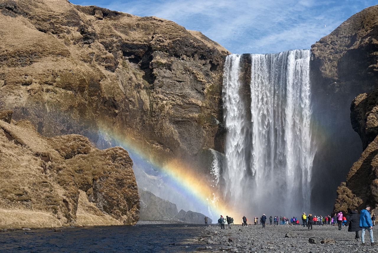 Turista in Islanda contempla paesaggio vulcanico con ghiacciai e cascate.