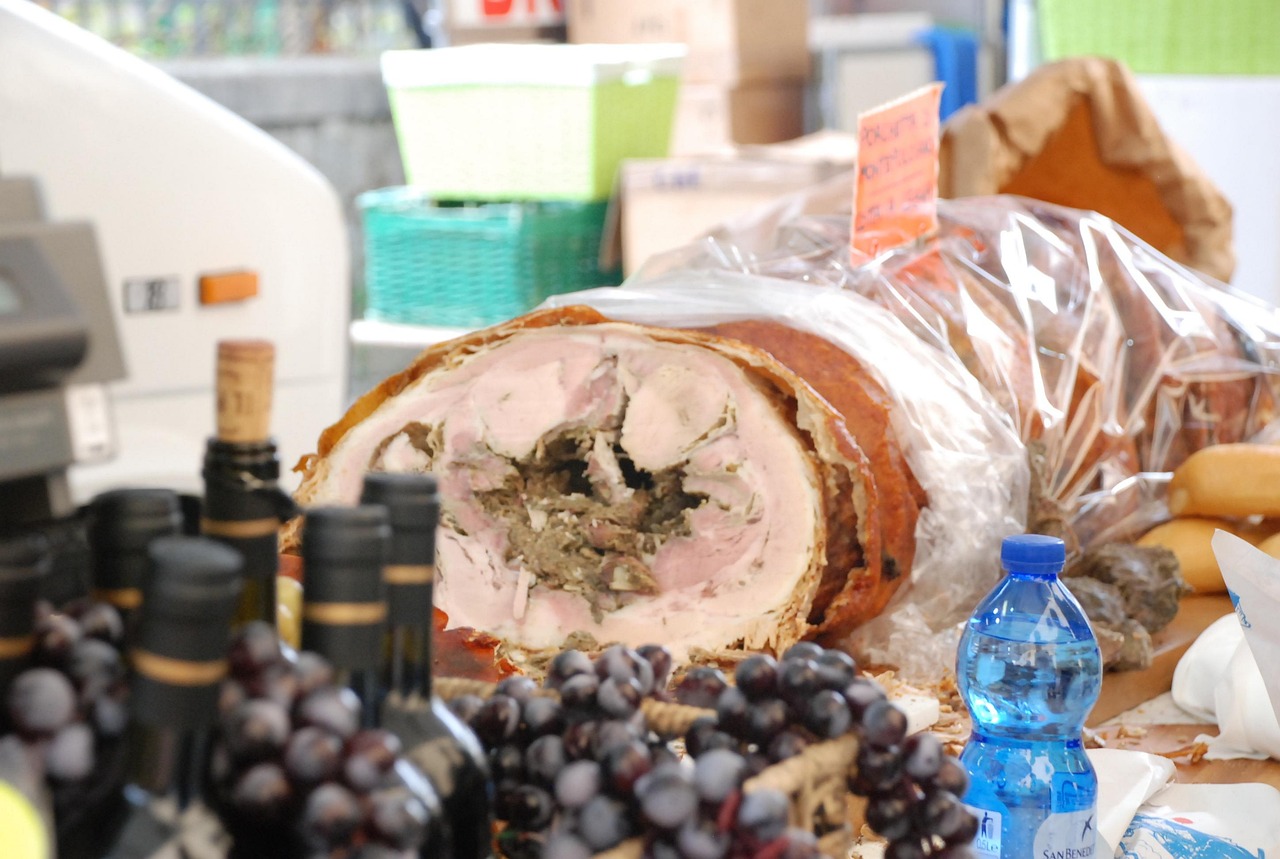 Mercato rionale di San Gimignano con bancarelle di vino toscano e visitatori che degustano prodotti locali.